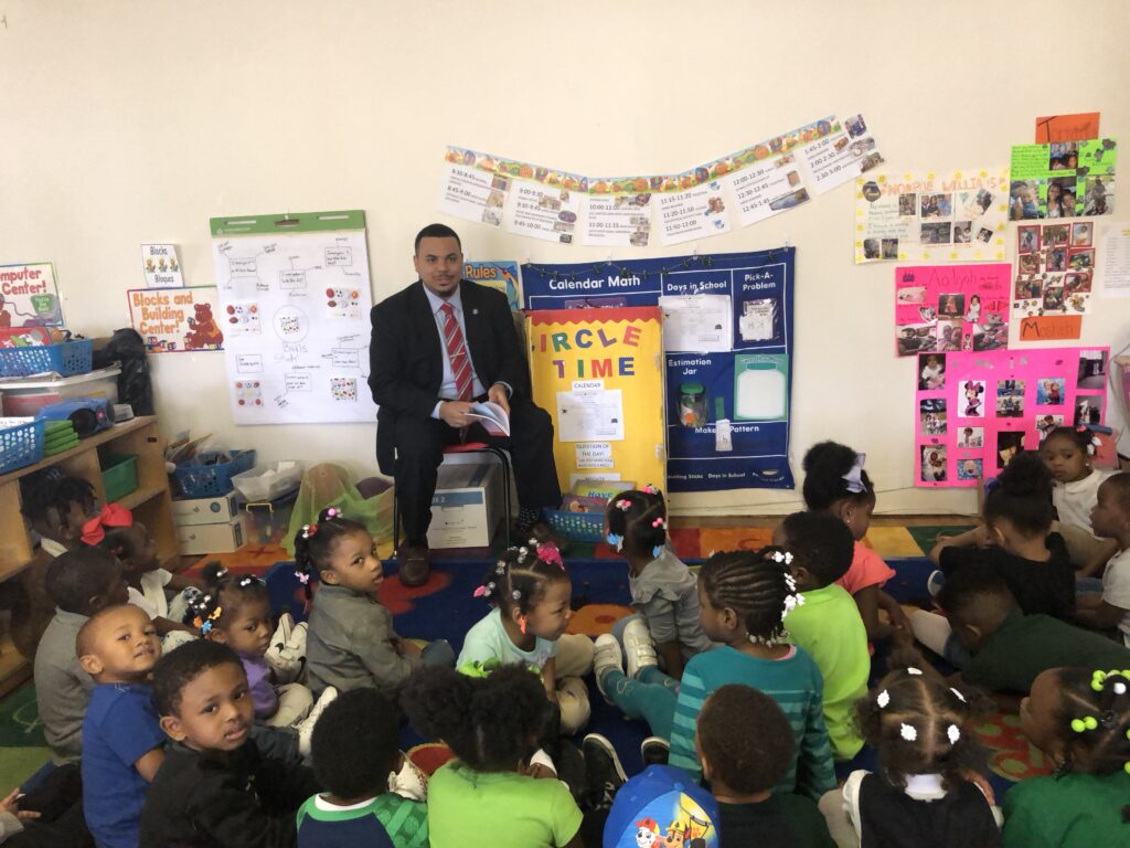 Rep. Derek Mallow reading to a group of young school children.